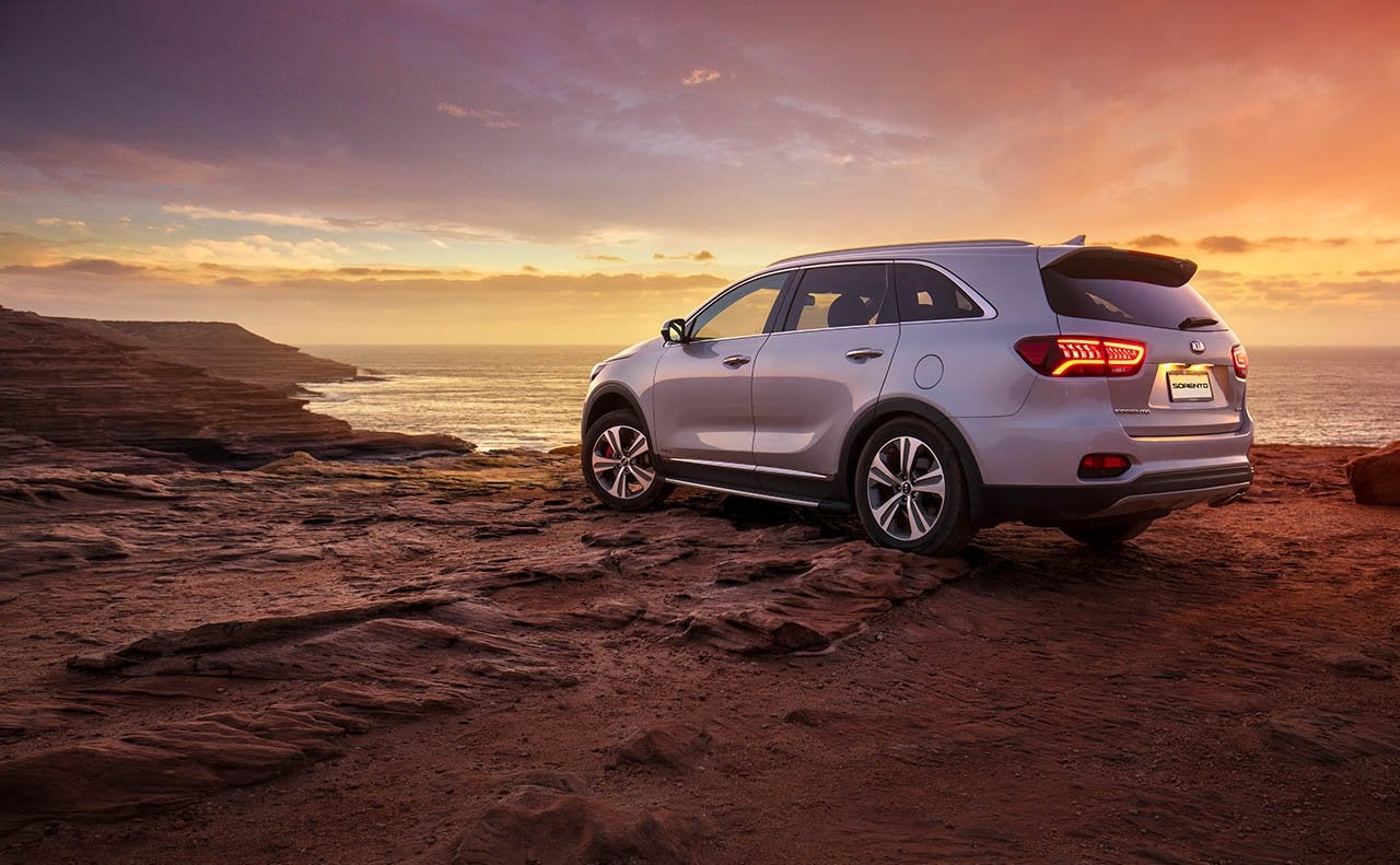 Image of a white Kia Sorento parked in the desert at sunset.